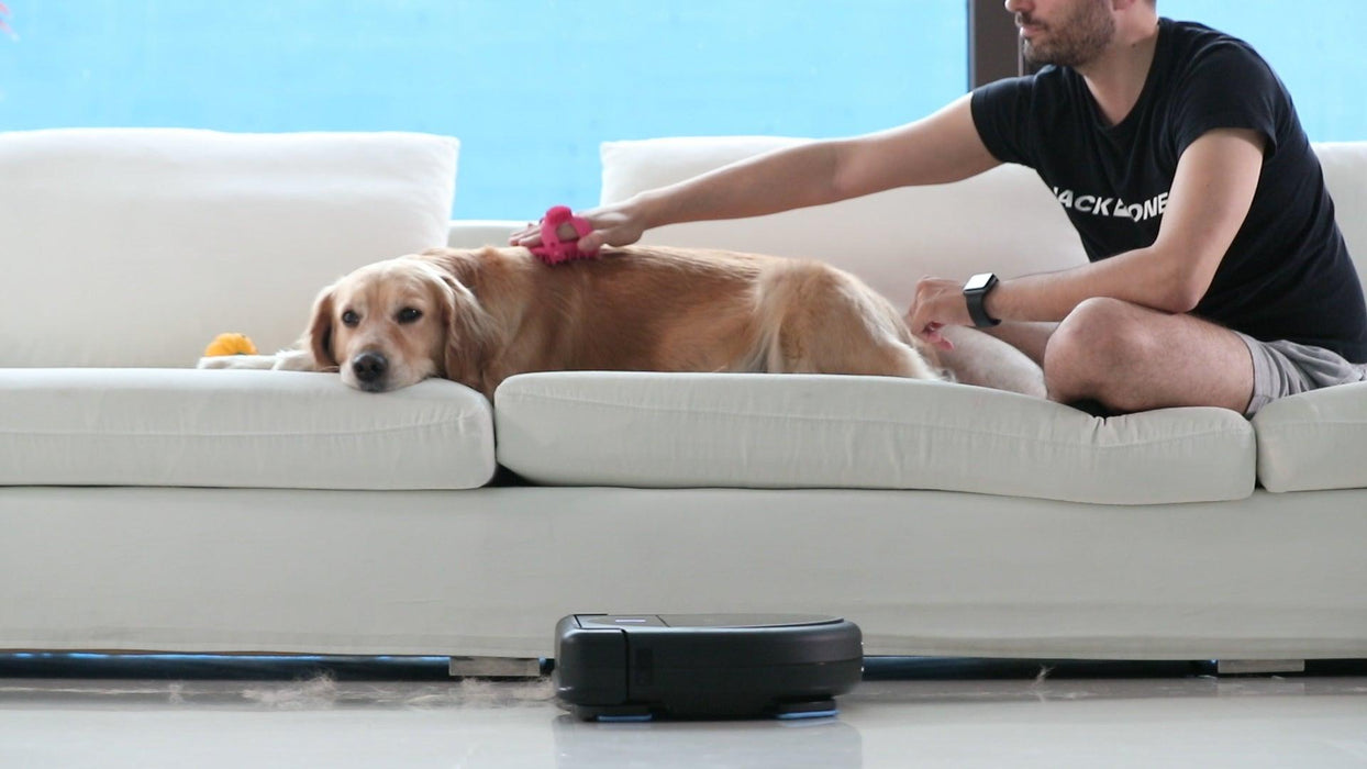 guy petting dog with vacuum robot